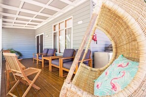 Un espacio al aire libre cubierto con muebles de madera y una silla de mimbre.