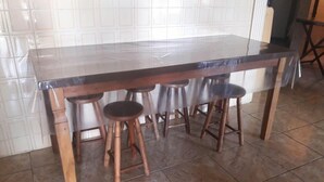 A kitchen with a marble countertop, four wooden stools, and tiled flooring. - House with pool 200 meters from the beach (Prainha)