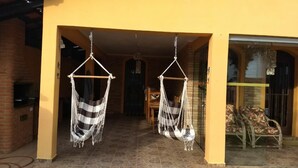 A building with a yellow exterior, a brick fireplace, and two hammocks hanging from the ceiling. - House with pool 200 meters from the beach (Prainha)
