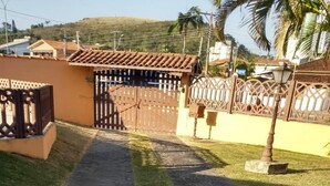A paved pathway leading to a gated entrance with a fence and a lamp post. - House with pool 200 meters from the beach (Prainha)