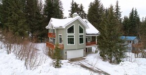 Situated in a wooded area, this two-story home offers a secluded retreat with a front porch and attached garage.