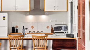 A kitchen with wooden beams, white cabinets, a gas stove, and a microwave.