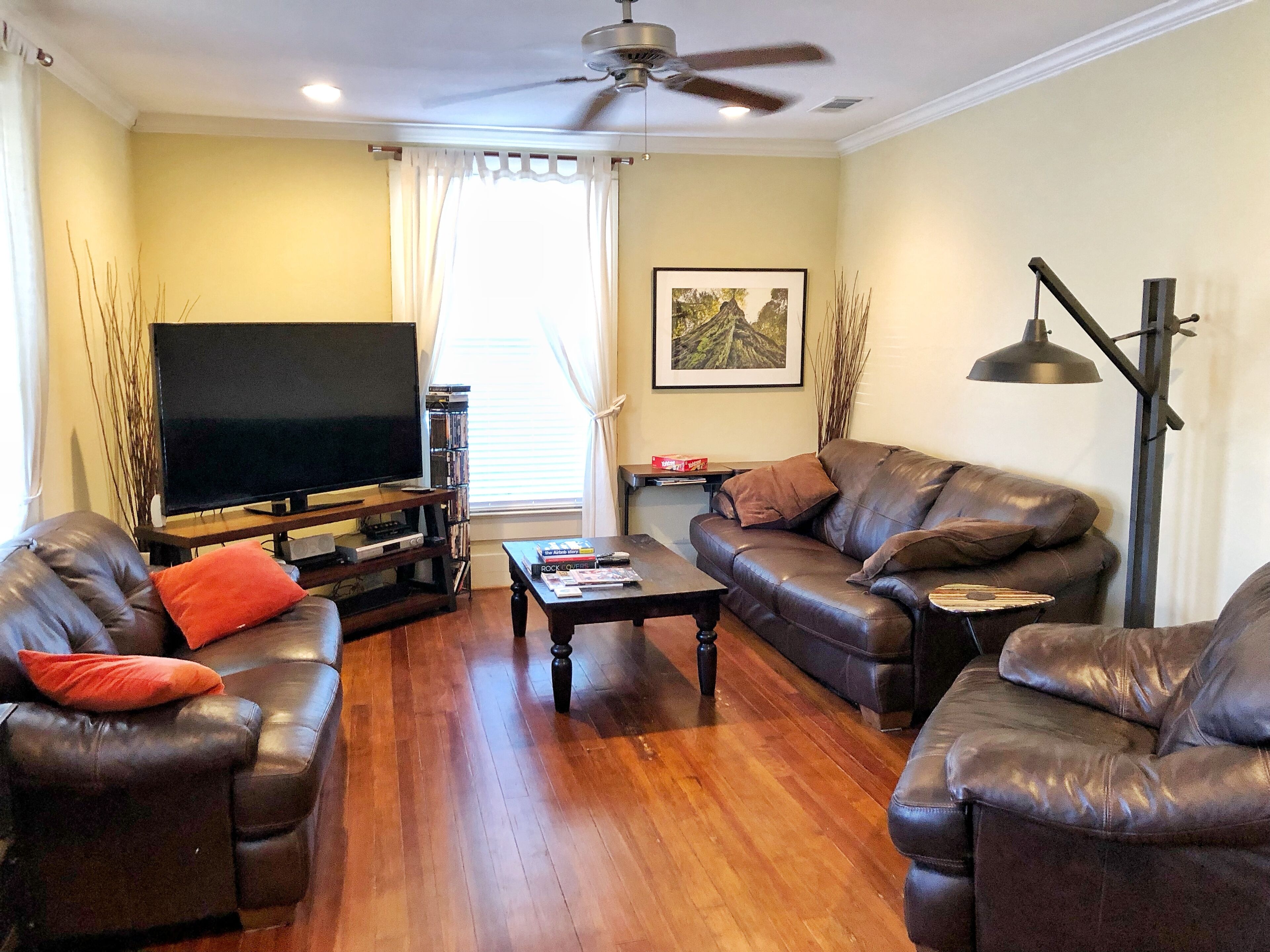 A living room with a flat-screen TV, leather sofas, a coffee table, and a bookshelf.