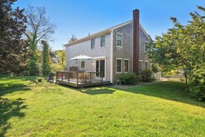 A two-story house with a deck, a chimney, and a well-maintained lawn. - Perfect Relaxation Spot 5 min to Beach! (Eastham)