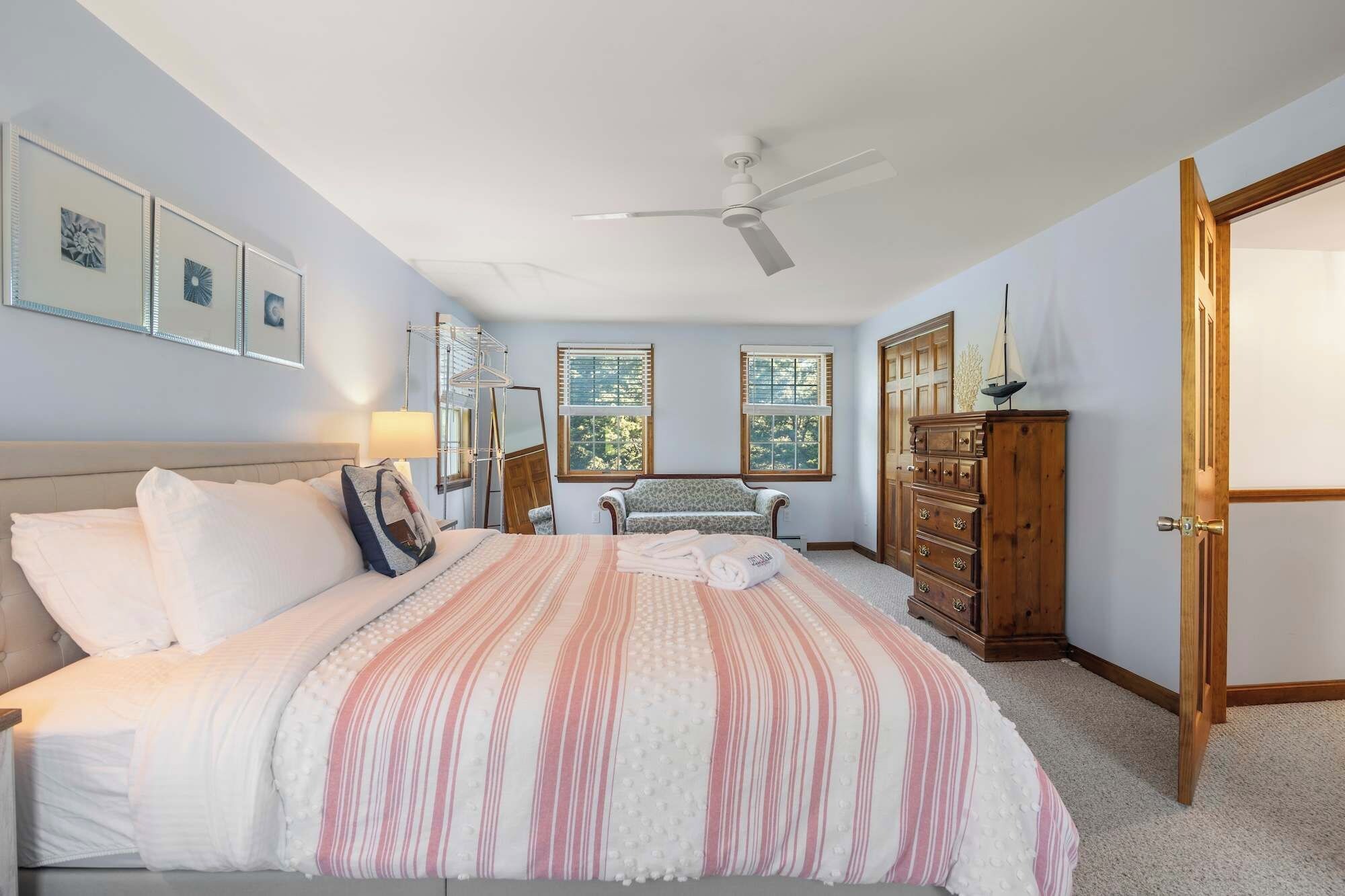 Un dormitorio con cama, cómoda, banco y ventilador de techo.