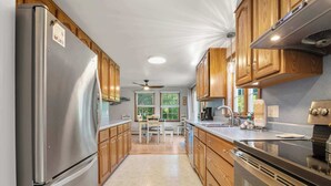 A modern kitchen with wooden cabinets, stainless steel appliances, and a central island. - Perfect Relaxation Spot 5 min to Beach! (Eastham)