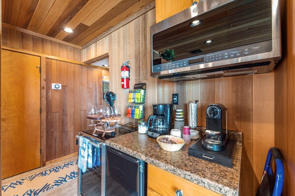 Una cucina con rivestimenti in legno, una cappa in acciaio inossidabile, una macchina per il caffè e un espositore per piatti.