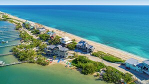 An aerial view of a coastal hotel with multiple buildings, a beach, and a marina.