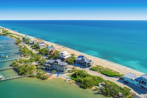 Vista aérea de un hotel costero con varias construcciones, una playa y un puerto deportivo.