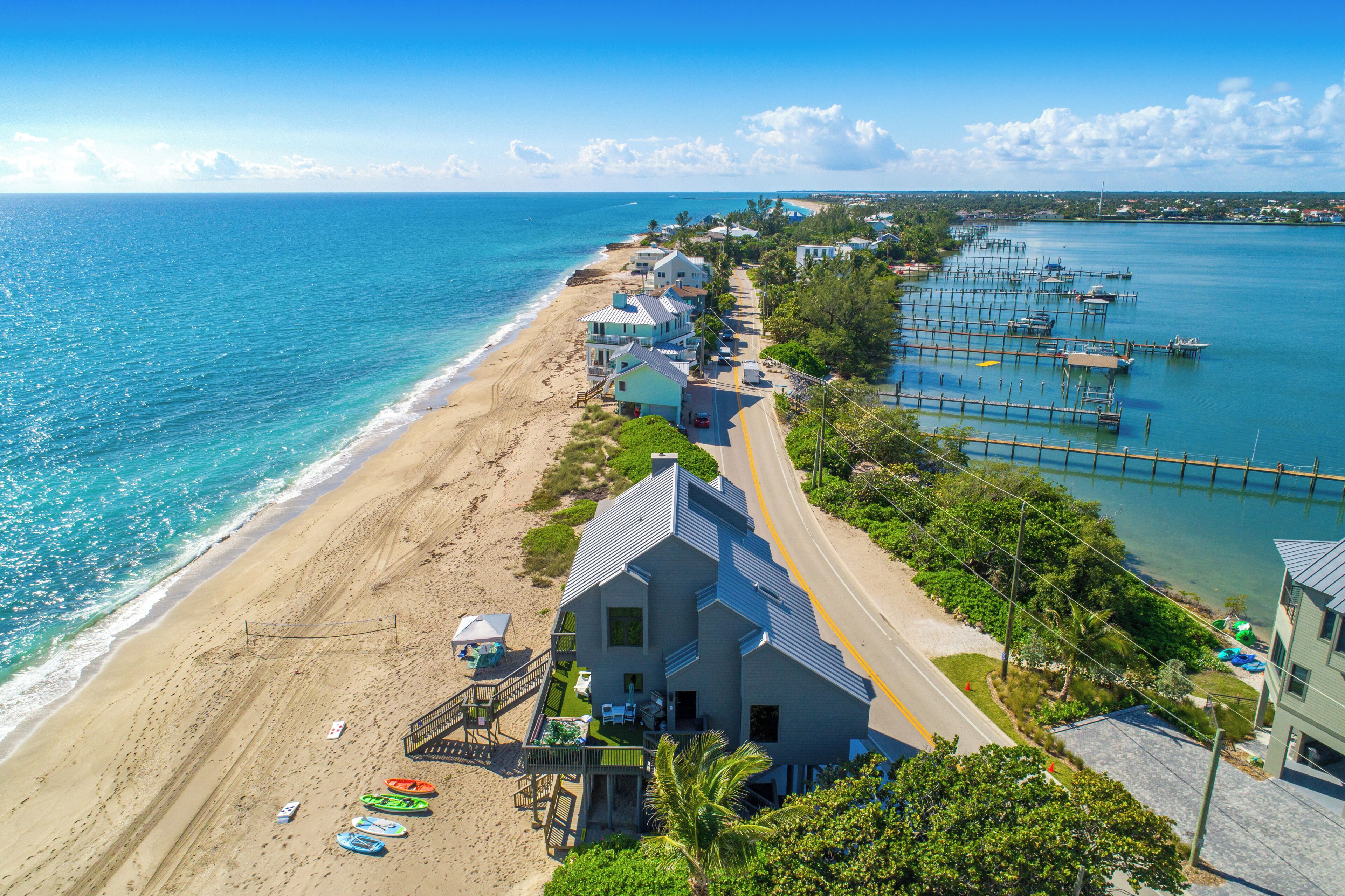 A coastal property with a beach, dock, and a large house with a balcony.