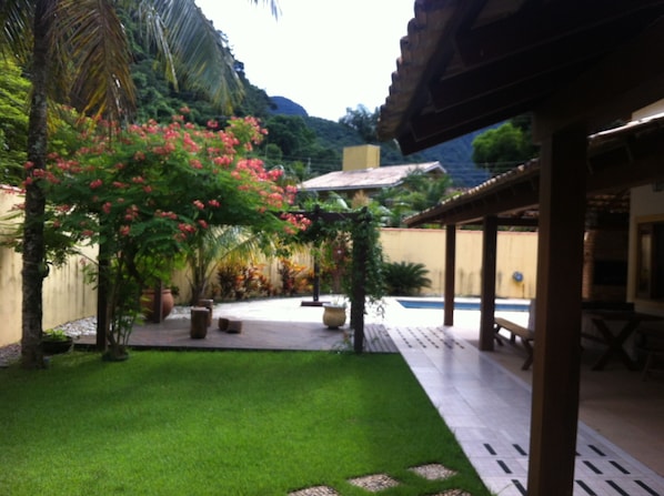 A courtyard with a pool, palm trees, and a pergola.