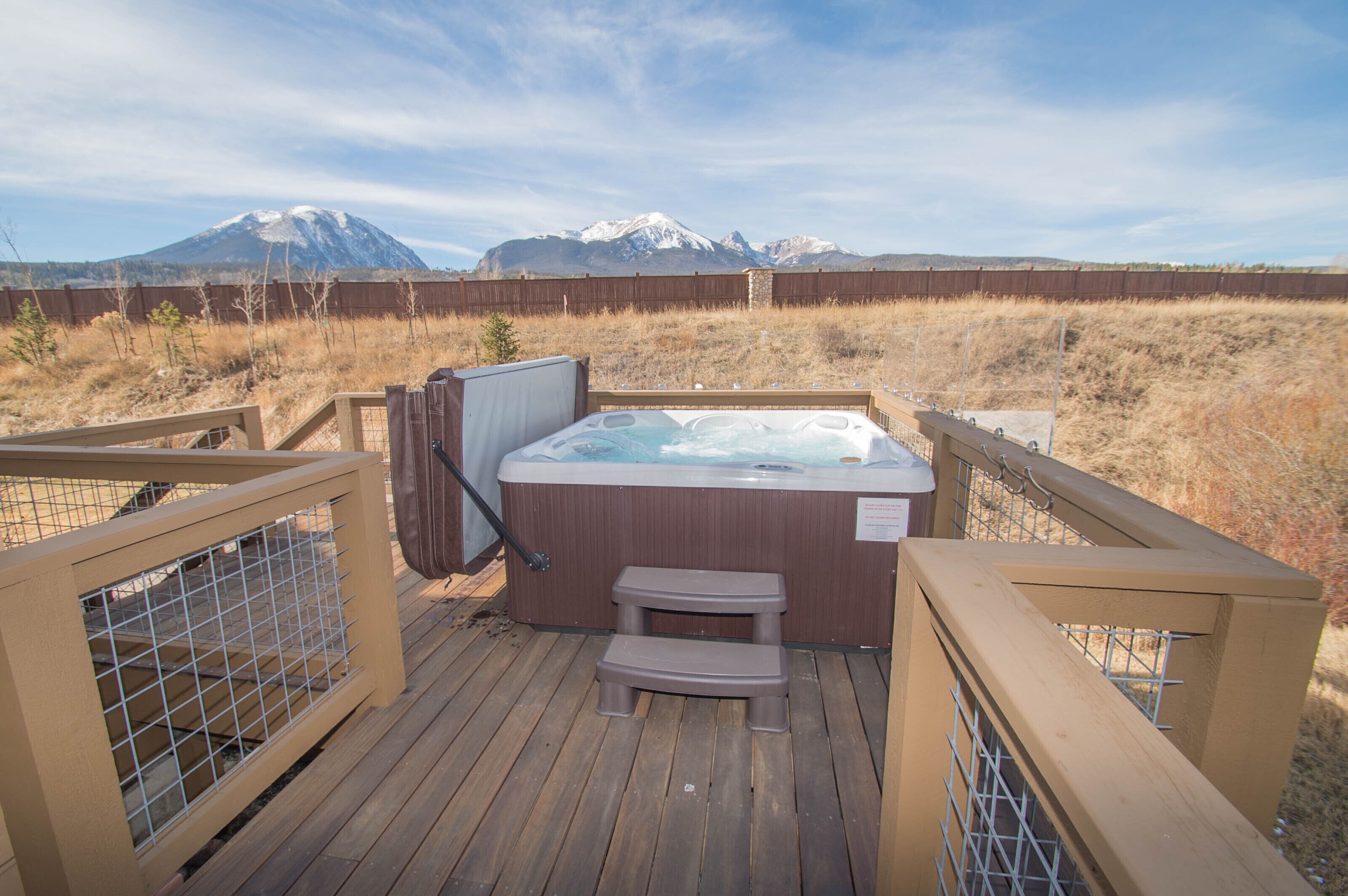 Un bain à remous sur une terrasse en bois, avec une vue sur les montagnes en arrière-plan.