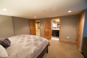 Un dormitorio con una cama, un armario de madera y un baño visible a través de una puerta abierta.