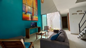 A modern living room with a teal wall, a large sailboat painting, a wooden chair, a gray sofa, and a staircase. - Casa Luna. Welcome Family To Enjoy A beautiful beach ! (Chelem)