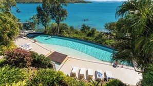 Piscina com vista para o mar e colinas.