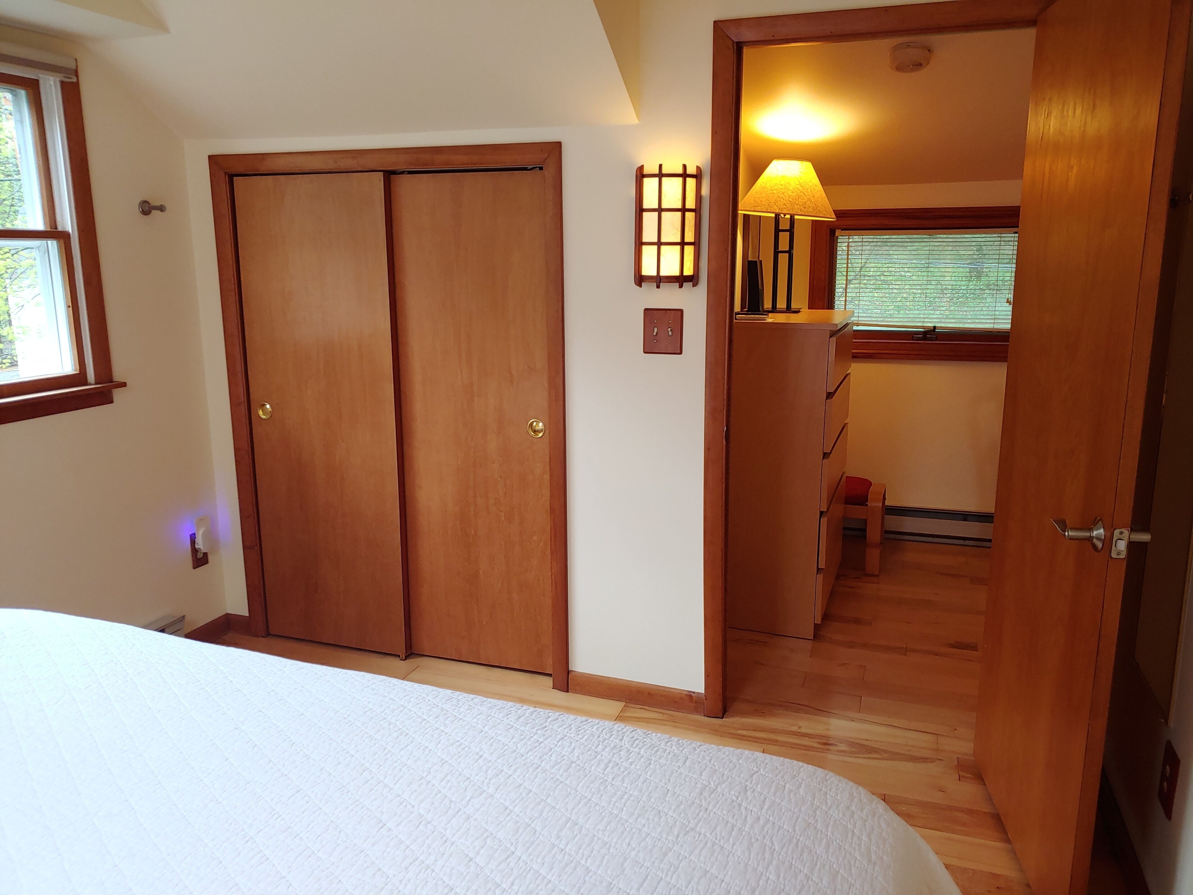 Une chambre à coucher avec un grand lit, une armoire en bois et un petit bureau avec une lampe.