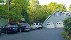 A parking area with several cars, a basketball hoop, and a building with a garage. - Spacious and comfy, king bed, double futon sofa, kitchen, near Colgate, 7 Oaks (Hamilton)