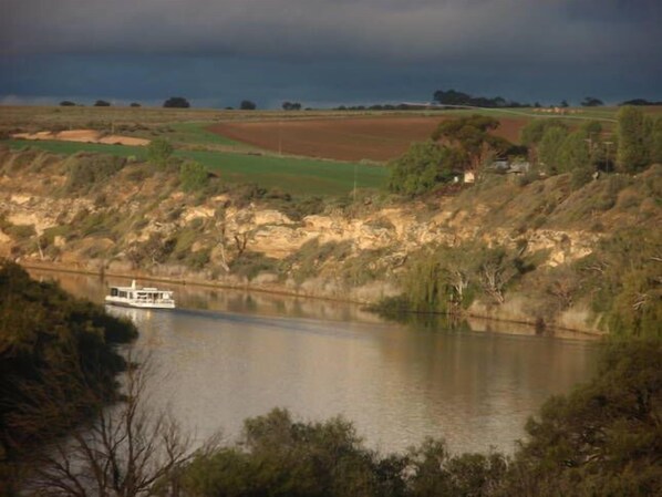 A river with a boat, surrounded by hills and fields.