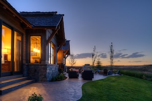 A modern house with a stone foundation, large windows, and a patio area with outdoor furniture. - Spectacular 5 Bedroom Villa On 7th Hole At Tributary  with Private Hot Tub (Driggs)