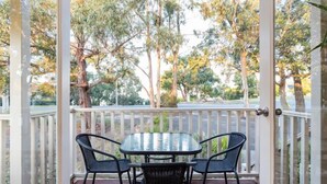 A covered outdoor area with a glass table and four chairs, surrounded by a white railing and trees in the background. - Time to wind down, hear the birds, the Sea. New EV Charger.
Double Spa Bath. (Lorne)