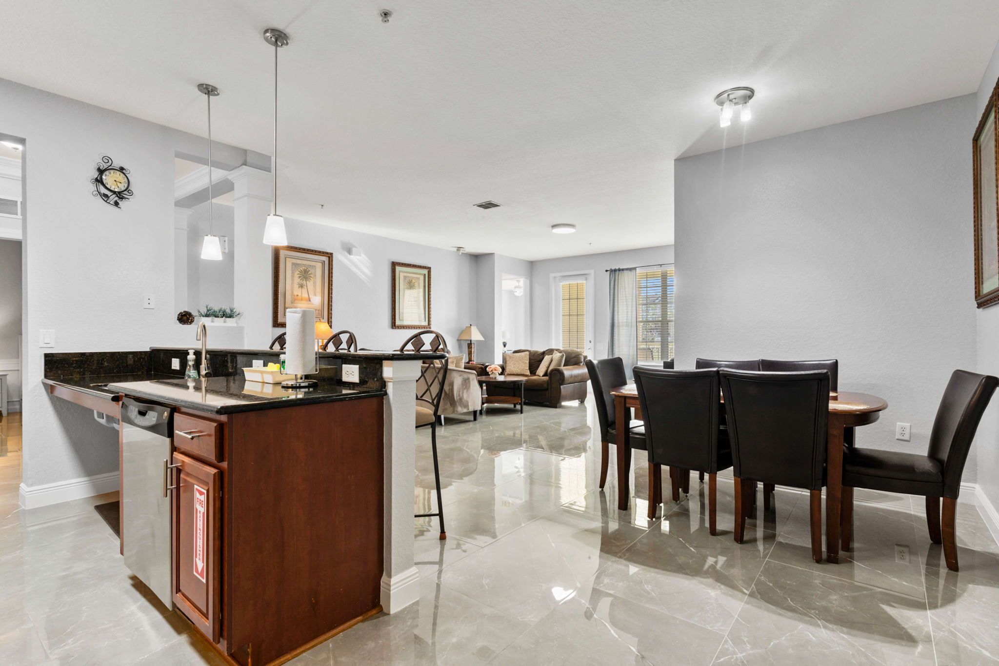 Een moderne keuken met een centraal eiland, een eetgedeelte met stoelen en een woonkamer met een bank en salontafel.