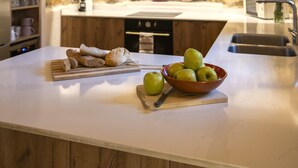 Een keuken met een stenen muur, een houten aanrecht en een schaal met appels.