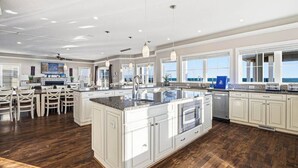 Een ruime keuken met een groot schiereiland, witte kasten en uitzicht op de oceaan.