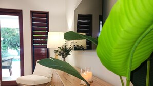 Una sala de estar moderna con una mesa de centro de madera, un sillón blanco y una planta verde grande.