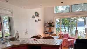 A kitchen with a large island, wooden flooring, and a view of a lake through large windows. - Full Moon on the Harraseeket, Freeport, Maine   (Freeport)