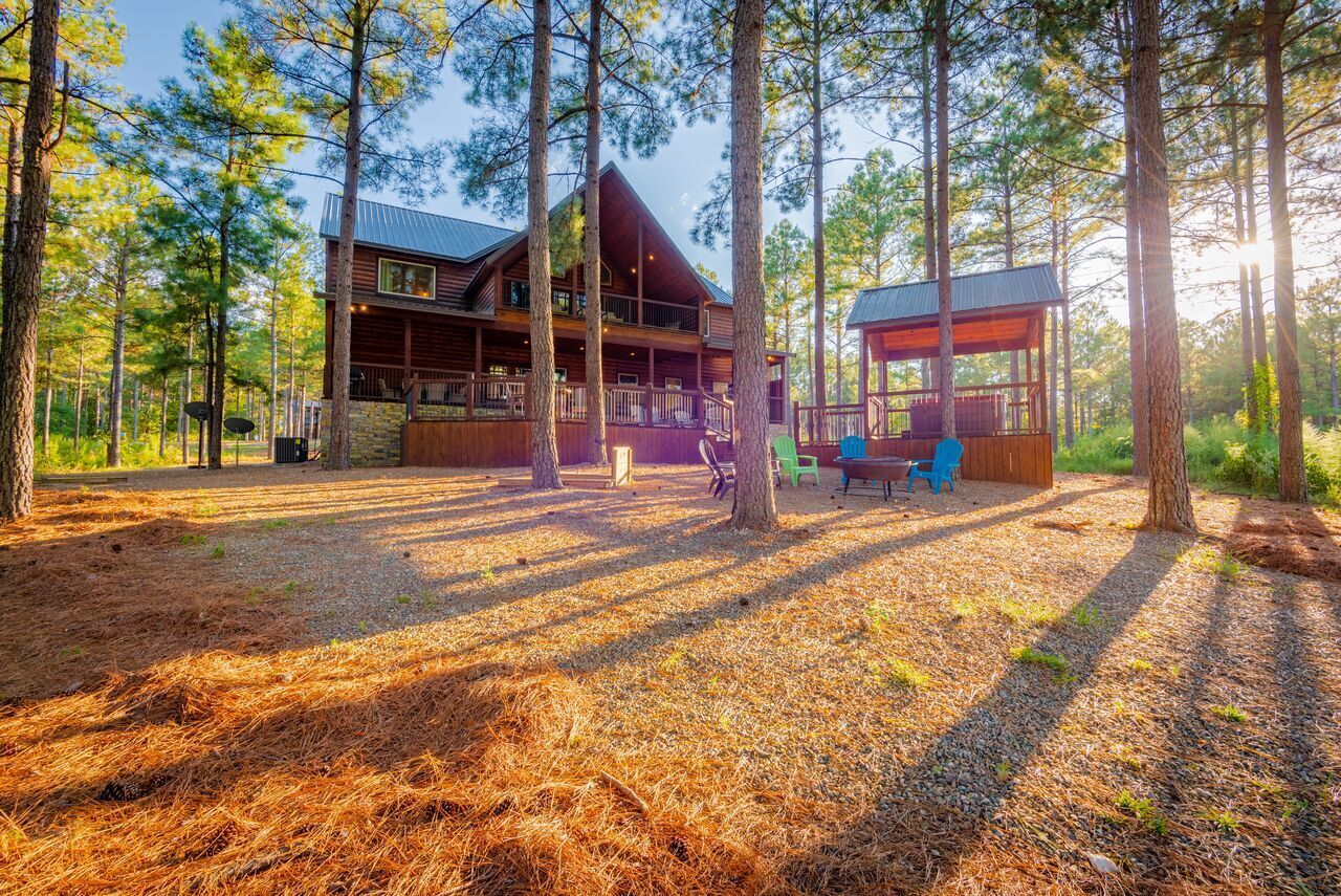 Une cabane dotée d’une grande terrasse, entourée de grands pins.