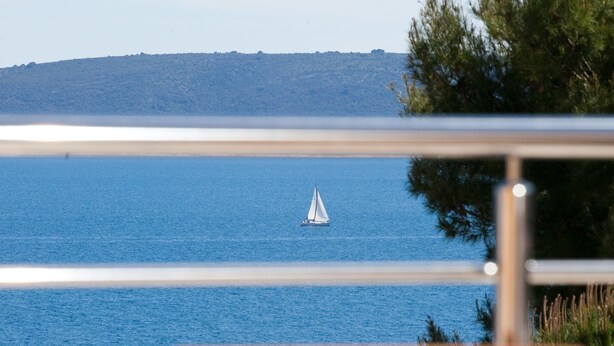 Ein Tisch mit Blick auf das Meer und ein Segelboot in der Ferne.