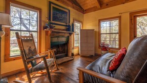 Un salon chaleureux avec une cheminée, des meubles en bois et de grandes fenêtres.