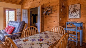 L’intérieur d’un chalet en bois chaleureux et accueillant, avec une table à manger, des chaises, un canapé en cuir et une décoration murale sur le thème du Texas.