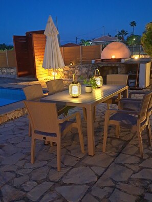 An outdoor patio with a stone table and chairs, surrounded by a pool and a stone wall. - Beautiful Villa Ella with private pool.  E.O.T Licence MHTE 0428K9200476001 (Zakynthos (Zante))
