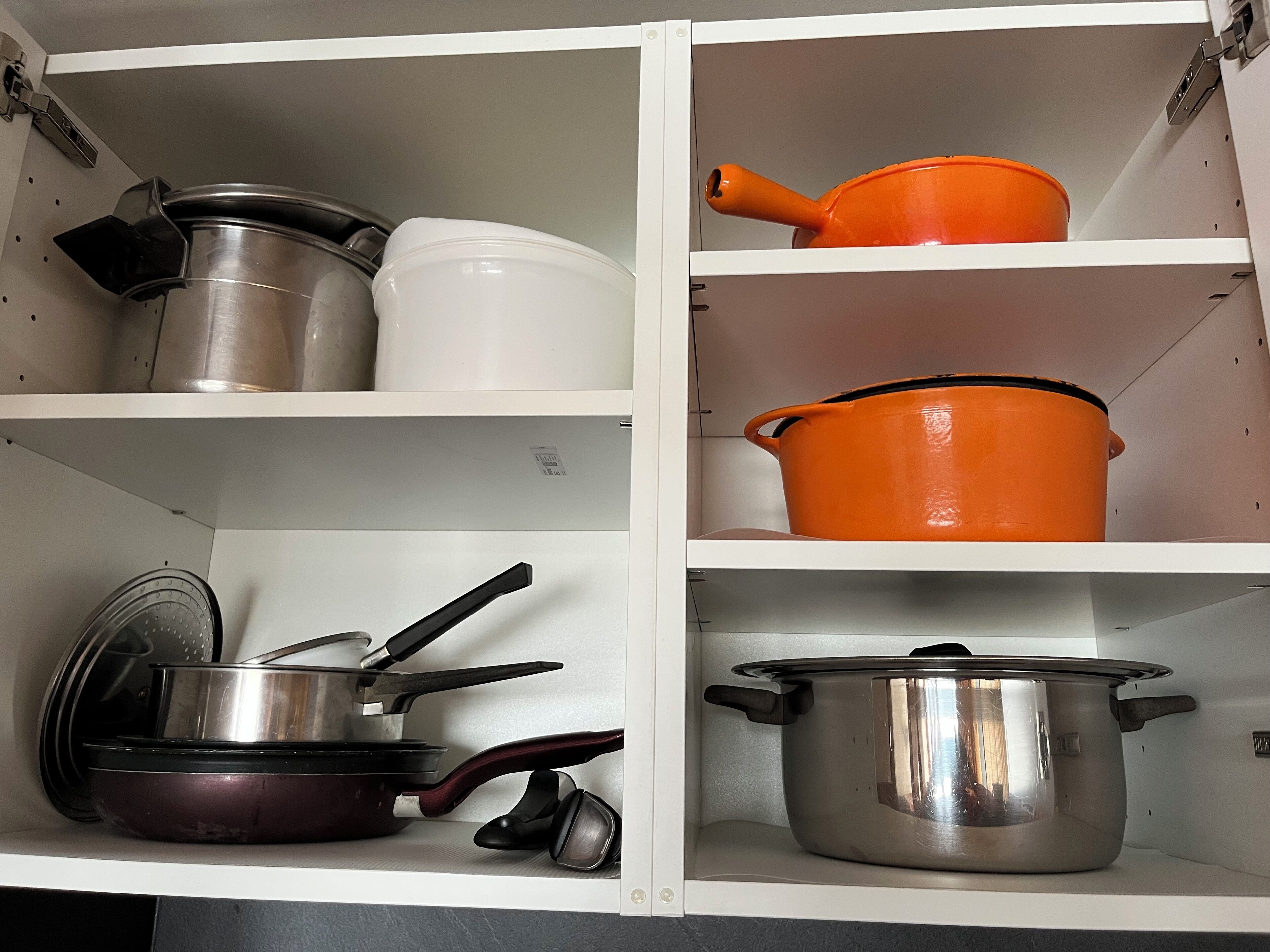 Un armario de cocina con varias ollas y sartenes.