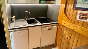 Uma cozinha compacta equipada com micro-ondas integrado, pia e lava-louças.