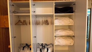 Um closet espaçoso com várias prateleiras, cabides e sacos organizadores.