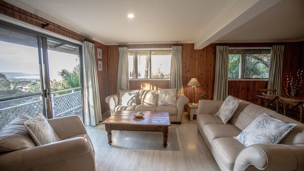 Uma sala de estar espaçosa com uma janela grande, um conjunto de sofás, uma mesa de centro e um abajur.