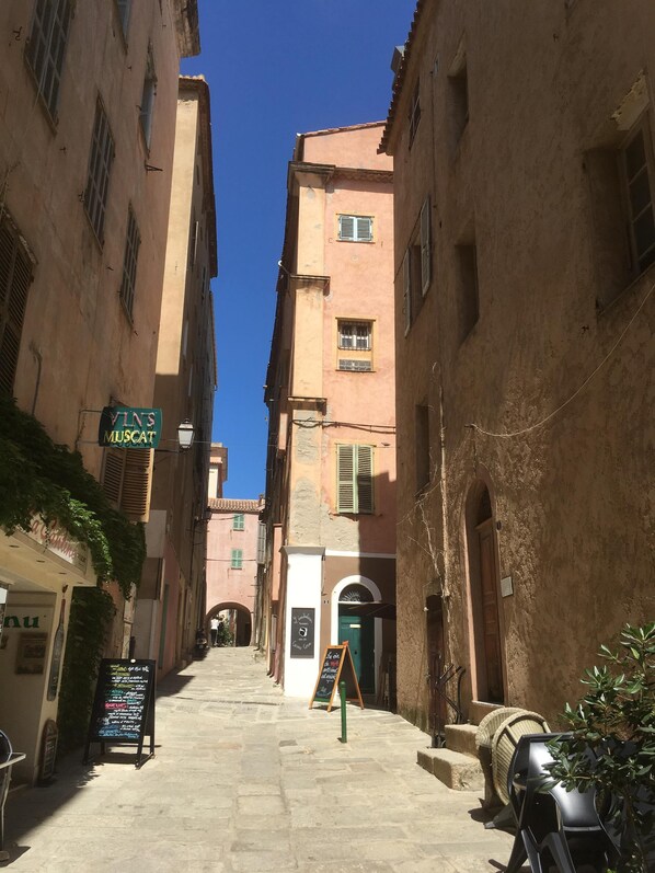 A narrow street with buildings on either side, a signboard with a menu, and a green door. - Exceptional sea view! Apartment facing the sea, central Rousse Island (L'île-Rousse)