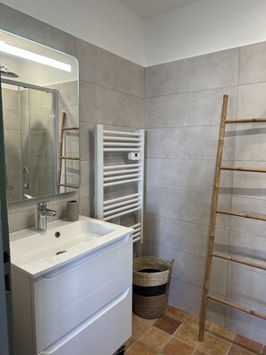 A bathroom with a white sink, a mirror, a glass shower enclosure, a white towel rack, and a wooden ladder. - Exceptional sea view! Apartment facing the sea, central Rousse Island (L'île-Rousse)