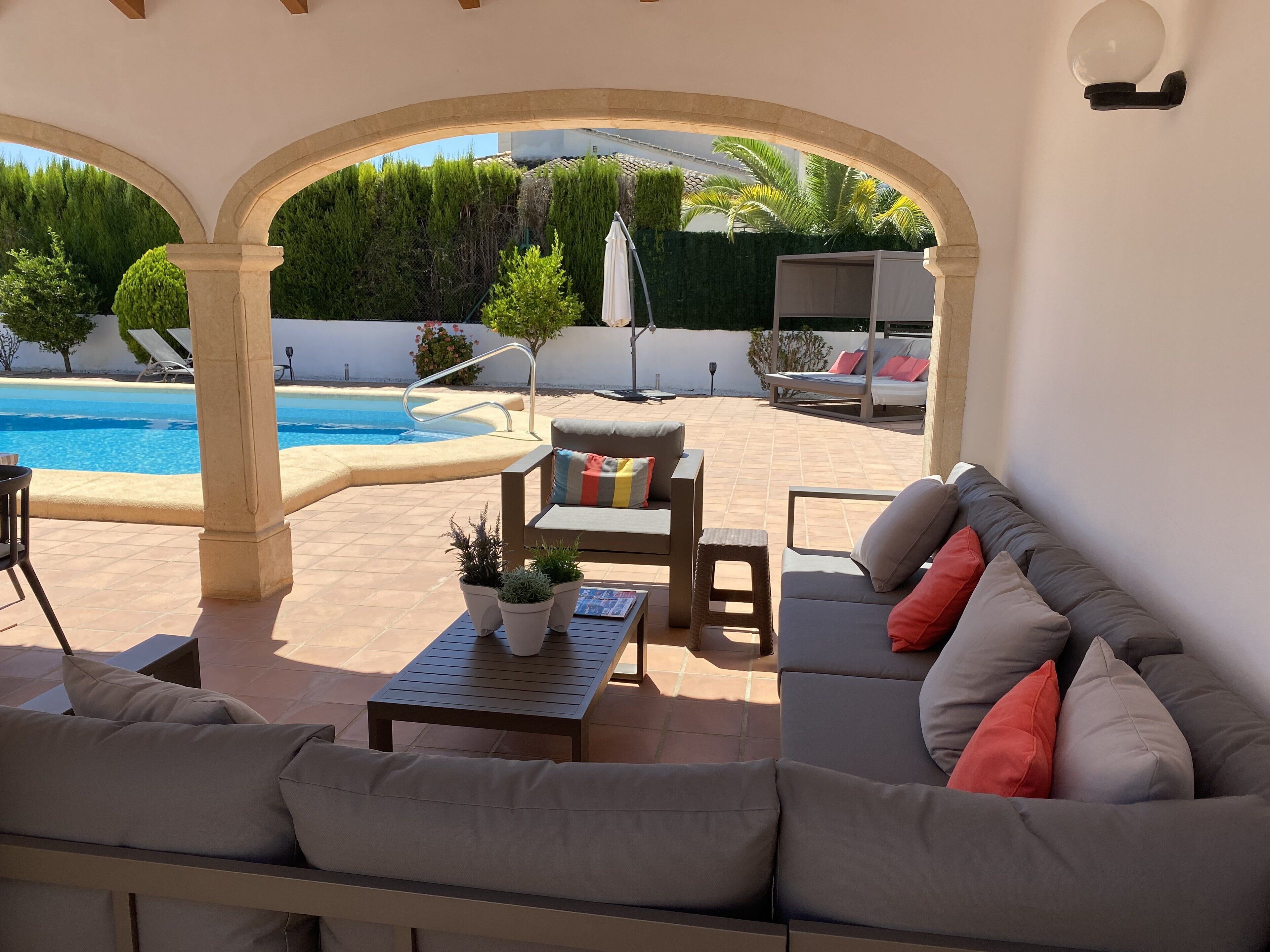 An outdoor patio area with a pool, seating, and potted plants.