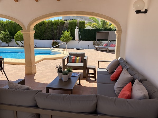 Ein Außenbereich mit Terrasse, Pool, Sitzgelegenheiten und Topfpflanzen.