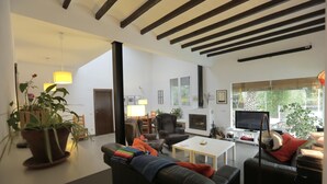 Ein modernes Wohnzimmer mit einem schwarzen Ledersofa, einem weißen Couchtisch und einem Kamin. Es gibt zwei Sessel, einen Fernseher und eine Topfpflanze.