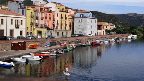 Una orilla con edificios coloridos, una vía acuática tranquila y barcos amarrados a la costa.