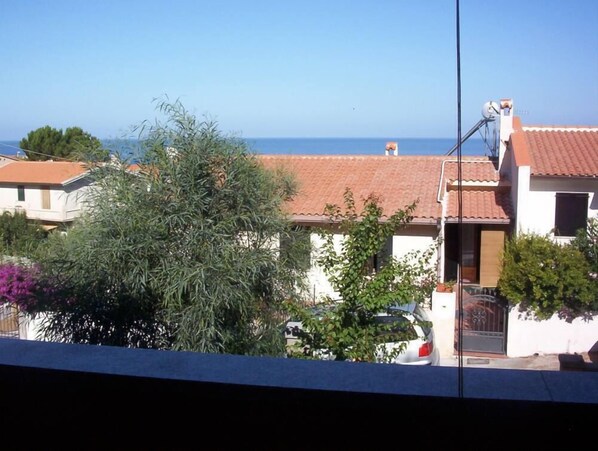 A residential area with houses, a car, and a clear view of the sea.