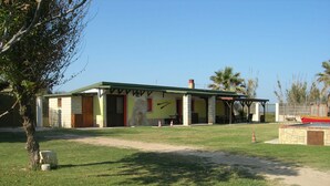 Un edificio con techo verde, paredes de piedra y un patio cubierto.