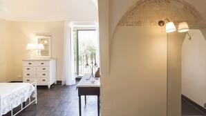 Een slaapkamer met een bed, een dressoir, een tafel en een lamp.