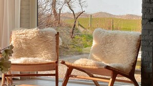 Ein modernes Wohnzimmer mit zwei bequemen Sessel, einem Couchtisch und Blick auf eine ländliche Landschaft durch große Fenster.