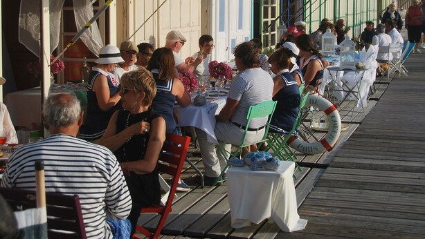 Eine Reihe von Strandhütten aus Holz mit Tischen und Stühlen, die zum Essen bereitstehen.