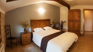 A bedroom with a wooden headboard, a bed with white bedding, a nightstand with a vase of flowers, and a wooden wardrobe. - Casa Rural Aranaratxe for 8 people (Aranarache)